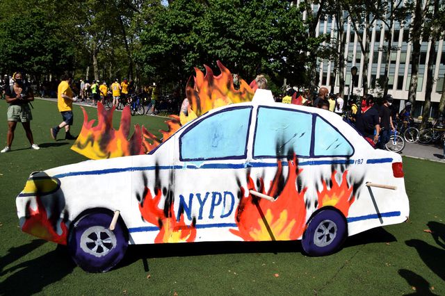 A photo of a cardboard cutout of an NYPD car on fire at the All Black Expo in Brooklyn on July 30th